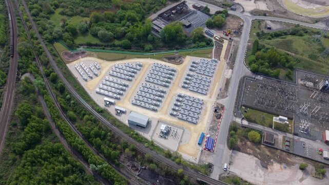 High angle aerial drone view of a massive battery energy storage system BESS facility with rows of containerized power units for national grid stability in Ferrybridge West Yorkshire UK