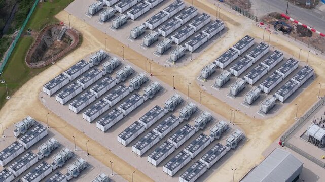 High angle aerial drone view of a massive battery energy storage system BESS facility with rows of containerized power units for national grid stability in Ferrybridge West Yorkshire UK