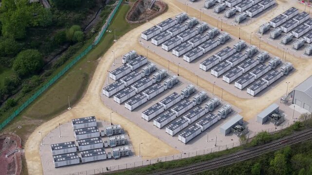 High angle aerial drone view of a massive battery energy storage system BESS facility with rows of containerized power units for national grid stability in Ferrybridge West Yorkshire UK