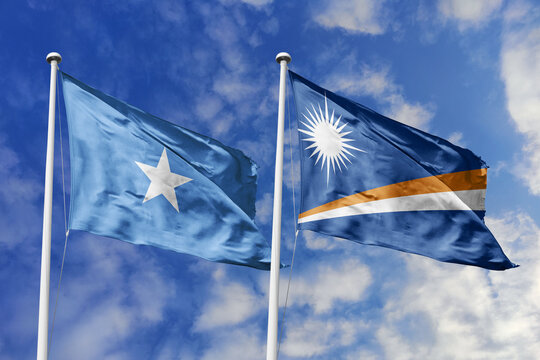Somalia and Marshall Islands flags waving in a clear blue sky, symbolizing a powerful diplomacy, expanding global trade, a strategic partnership, and a shared vision of unity for a sustainable future.