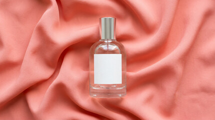 Naklejka premium A perfume bottle sits on a pink fabric background with a white label and silver cap.
