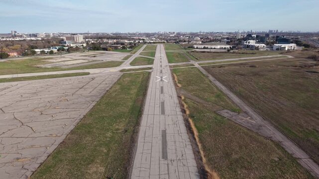 Cinematic aerial shot pulling back from the decommissioned runway 15/33 at Toronto Buttonville Airport (CYKZ), revealing the bustling Highway 404 and urban landscape of Markham, Ontario