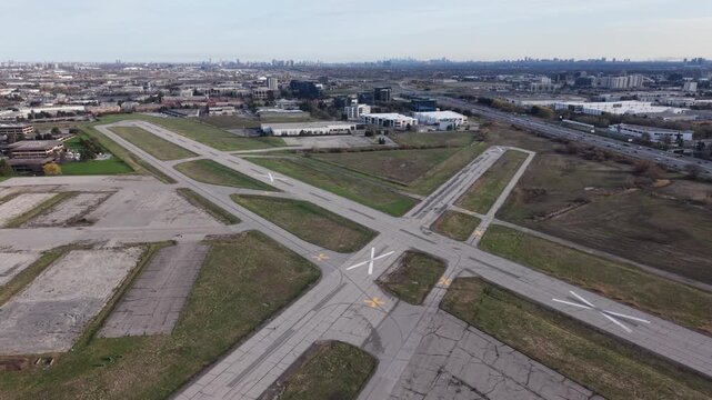 A wide aerial pull-back shot showing the vacant runways of the closed Buttonville Municipal Airport transitioning into the busy 16th Avenue and Highway 404 corridor in Markham