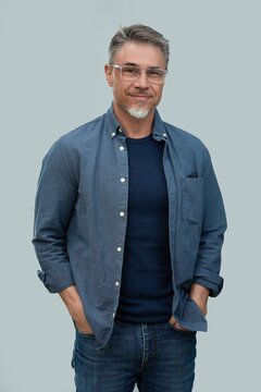Casual mid adult man standing hands in pocket. Portrait of happy middle aged male in 50s with gray hair and glasses, smiling. Isolated on white background.