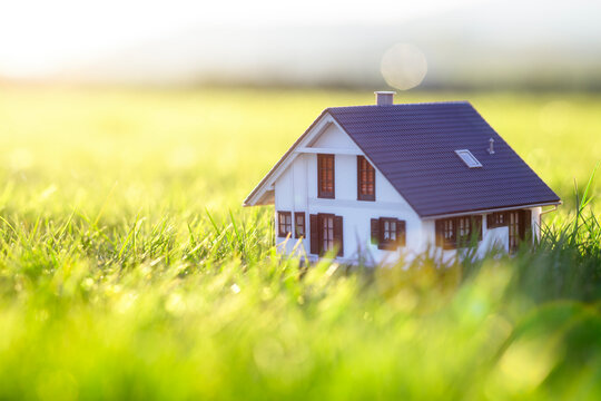 Model detatched house in empty field at sunset background concept for construction and real estate