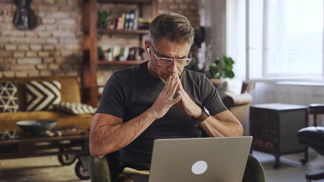 Mature man deep in thought while working on laptop at home. Remote working businessman looking for solution and new ideas. Male entrepreneur managing business online, thinking.