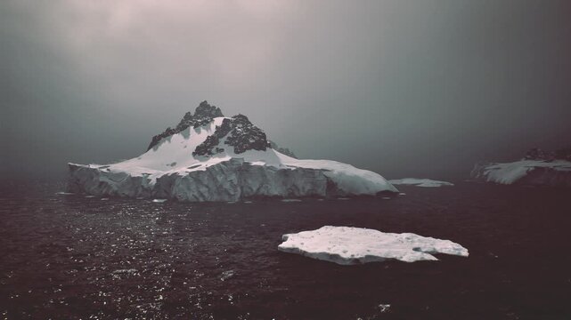 Icy iceberg floating on dark sea under soft sunrise light, distant jagged glacier, calm reflections on water, scattered ice fragments sparkling, tranquil