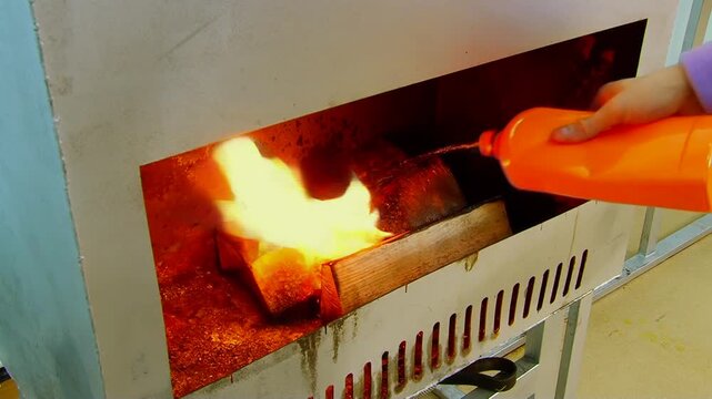Kindling comes to life inside a robust outdoor metal heater. Logs rapidly embrace brilliant, dancing flames, casting a vibrant, warm glow under the daylight sun.
