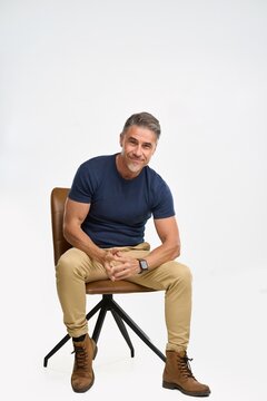 Confident mature man sitting on chair in studio portrait