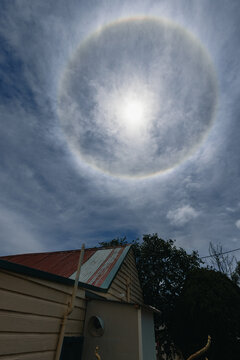 Sun halo appears in the sky above a house with a weathered roof