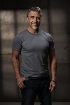 Portrait of confident mature man in casual standing on gray background. Happy older middle aged guy smiling. Healthy active, fit mid adult male in 50s.