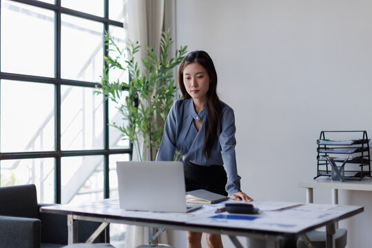 Asian business woman analyzing data on a laptop