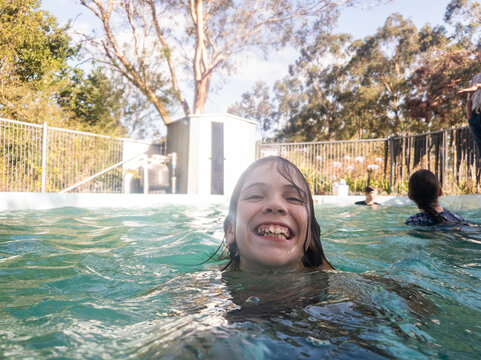 Australian tween girl swimming in backyard pool enjoying cool water