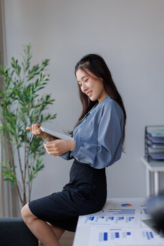 Young businesswoman analyzing financial data on tablet in office