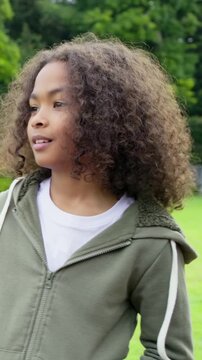 Boy in park responding to off-camera motion stepping closer smiling highlighting face for marketing