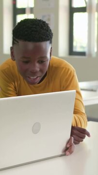 Vertical video: Leaning teen yellow tee tilting laptop at school to see, peer entering, greeting