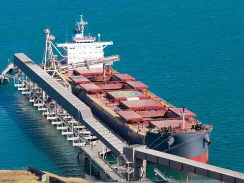 Aerial view of a cargo ship at a coastal wharf over a blue sea