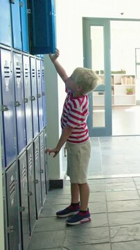 Vertical video: Girls moving aside boy striped T opening locker pulling backpack leaving at school