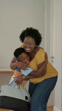 Opening tall wooden front door, mother in mustard blouse returning home, hugging son, holding tote