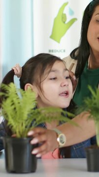 Vertical video: Pointing adult touching shoulder, child in denim reaching pots at table to learn