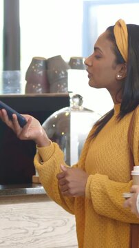 Smiling red-shirted barista in beanie taking payment at coffee counter with tablet, copy space