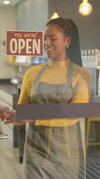 Vertical video: Flipping closed sign, barista pulling glass door to open cafe, wearing gray apron