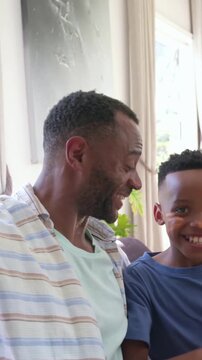 Vertical video: Reaching phone, father in striped top taking selfie with son at home, showing egg