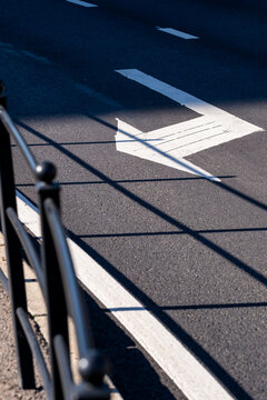 Daylight on asphalt road marking and shadow turns lines into abstract texture for urban safety concept in minimalist street surface detail