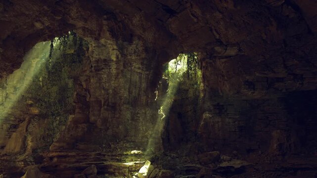 Filtered sunlight across small cave grotto, subtle green highlights on damp walls, inward sense of calm and solitude, textured rock shelves leading to soft