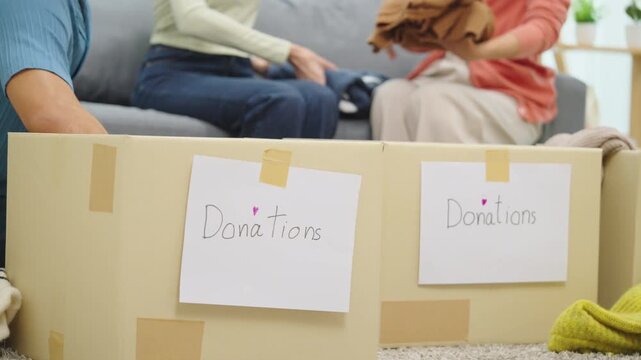 close up group of asian young adults sorting and packing clothes into donation box. community support, and charitable giving