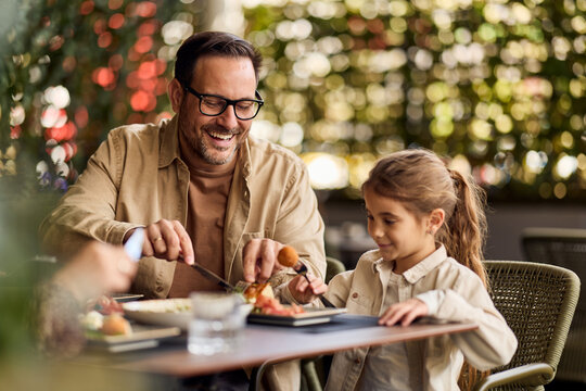 Father And Daughter Sharing A Meal At An Outdoor Cafe Smiling During Family Brunch