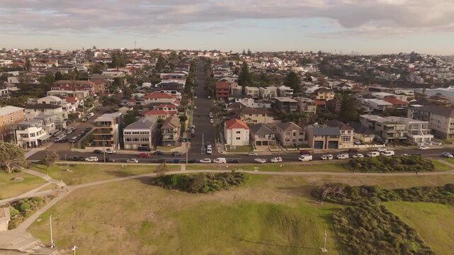 Sweeping aerial view of the Maroubra Beach residential coastline as the drone slides left revealing suburban streets and coastal parks under the soft glow of the late afternoon sun in Sydney