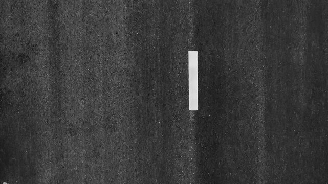 Top-down drone shot of an empty road with dashed white lines, representing direction, journey, logistics, road safety, minimalism, structured design, and efficient transport networks. 4k.
