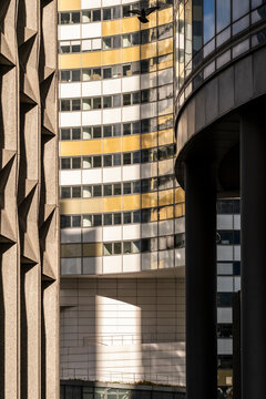 Sunlit columns framing curved corporate tower detail architecture facade office corporate urban abstract glass pattern modern district contrast