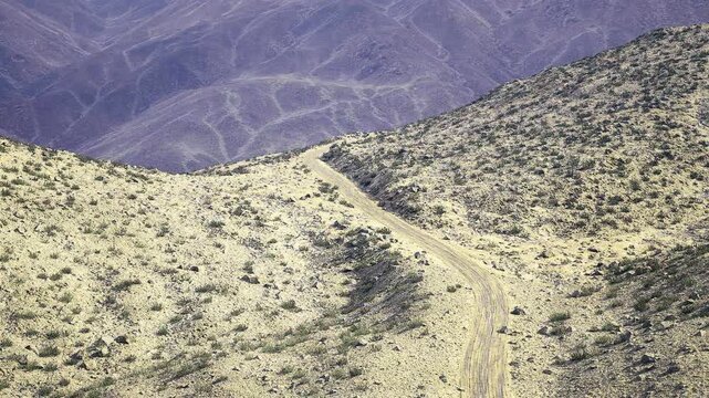 Aerial namibia contours revealing erosion patterns and meandering drainage lines across pale slopes with minimal vegetation and fine granular surface,