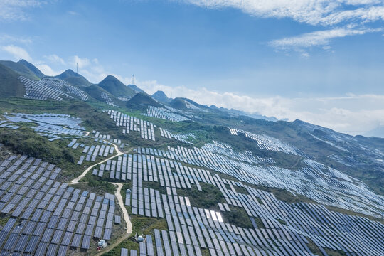 Vast Solar Farm Arrays Covering Rolling Mountain Ridges Under Blue Sky