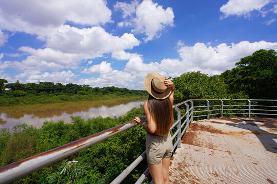 Rear view of young traveler woman on viewpoint enjoying the Pantanal with the Cuiaba River, Mato Grosso, Brazil