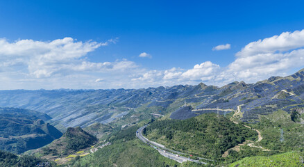 Naklejka premium Expansive Mountain Landscape with Solar Farms, Wind Turbines, and Highway Infrastructure