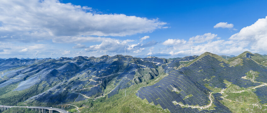 Panoramic View of Integrated Renewable Energy Landscape with Solar Terraces and Wind Turbines on Mountain Ridges
