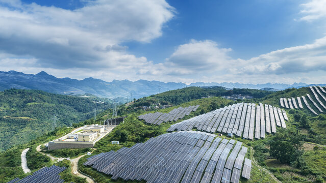 Solar Farm on Verdant Mountain Slopes Under Blue Sky with Clouds