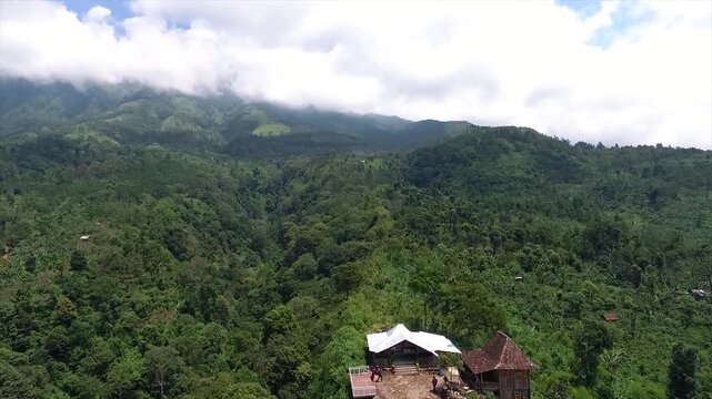 4K Drone View of a Remote Mountain Village in Indonesia with Lush Green Hills and Clouds.