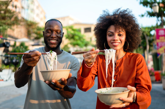 Diverse young friends enjoying street food together, sharing a happy, authentic multicultural moment