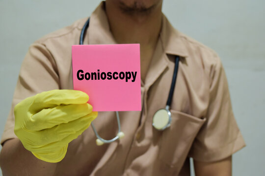 Doctor holds in hands a card with the name of the gonioscopy. Medical concept