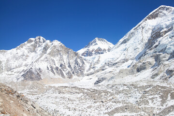 Obraz premium Everest base camp in off-season on the everest base trek, empty of tents and climbers, beneath himalayan peaks under a blue sky.