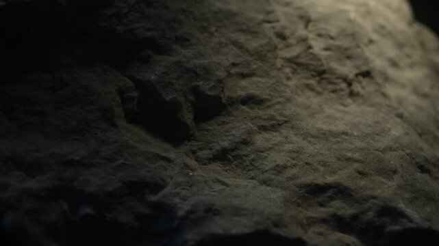 Cinematic camera move over dark rock texture with dramatic light