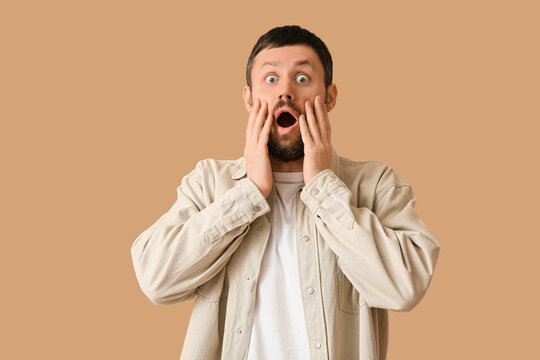 Shocked young man on beige background