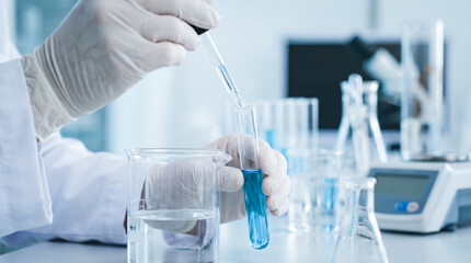 Fototapeta premium close up scientist hands wearing white gloves dropping blue liquid into glass test tube using pipette modern chemistry laboratory medical research experiment