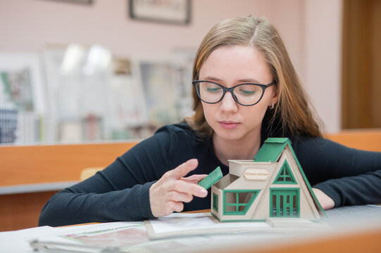 Caucasian young woman making a model of a building. Student of the construction university. 