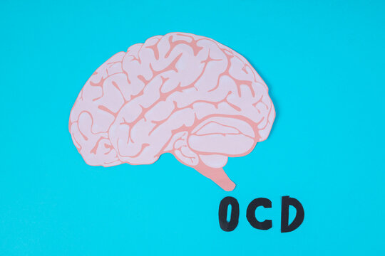 Top View Of Paper Brain Cutout With Black OCD Text On Blue Background For Mental Health Concept