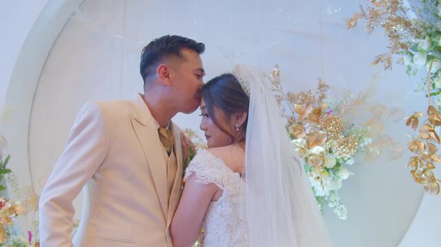 A joyful bride and groom sharing a romantic kiss, enjoying their wedding cake, and posing happily on a beautifully decorated stage during their wedding celebration.